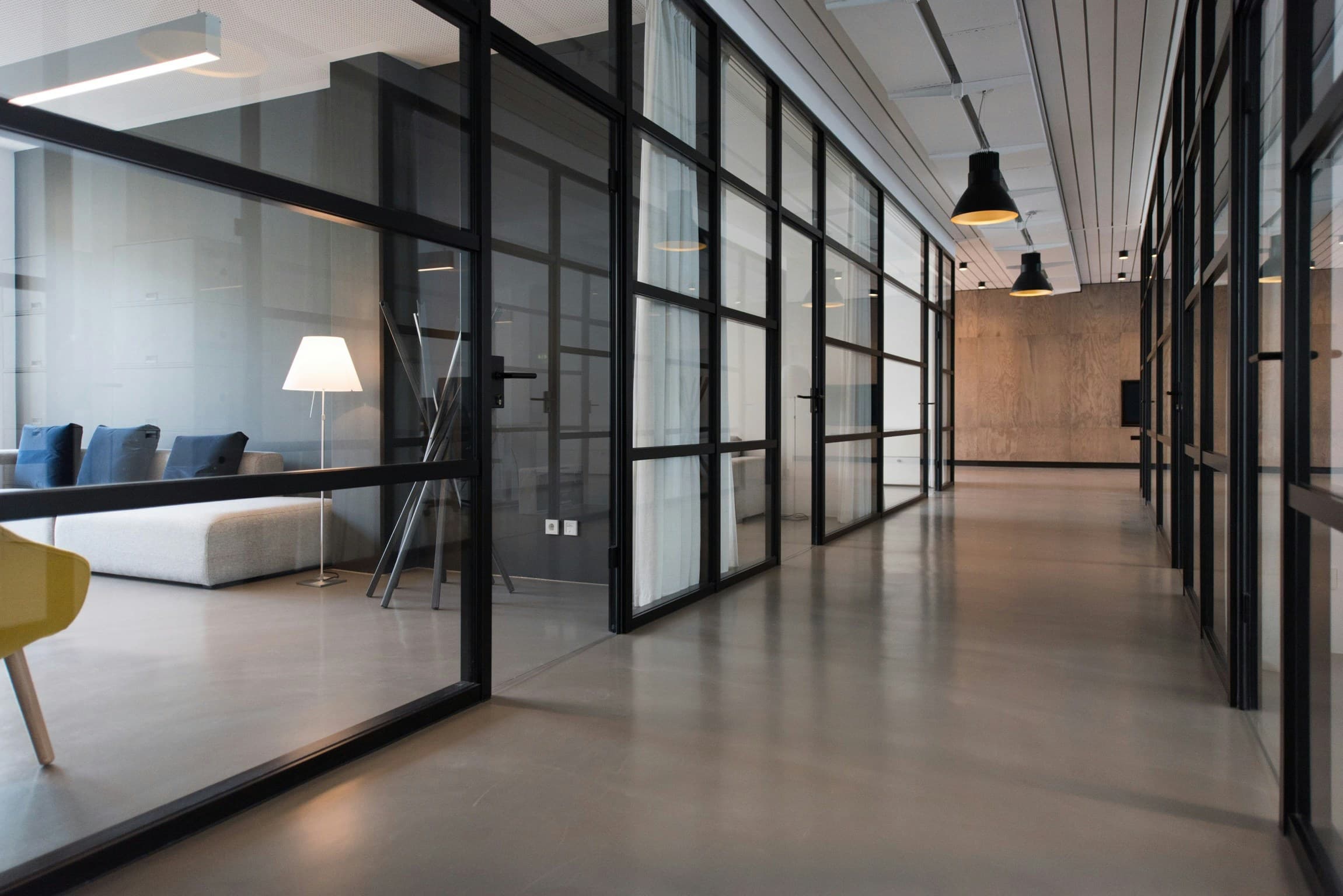 Leerer Bürogang mit Glastrennwänden bei Nacht.